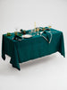 Table set with white plates, silverware, and glasses on forest green table cloth.