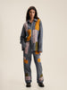 The model showcases a stylish blue and yellow patchwork suit, featuring denim patchwork trousers.
