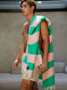 A man wearing a pink and green towel, branded as FUTAH x MUSTIQUE BEACH TOWEL.
