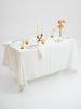 A beautifully set table with white laced linen table cloth and elegant place settings.